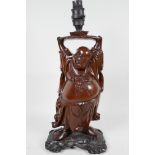 An Oriental hardwood lamp base carved as Hotai holding a lotus above his head which supports the