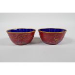 A pair of Chinese red ground porcelain tea bowls with polychrome decoration of flowers, foliage