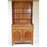 An Arts and Crafts oak one piece cottage dresser with rack, the single drawer with moulded detail