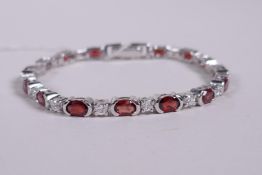 A silver bracelet set with alternating cubic zirconia and garnets, 6" long