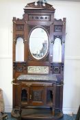 A Victorian walnut hall stand, with broken pediment top over an oval mirror with all over carved