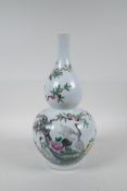 A Chinese polychrome porcelain double gourd vase decorated with storks beneath a fruiting peach