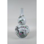A Chinese polychrome porcelain double gourd vase decorated with storks beneath a fruiting peach