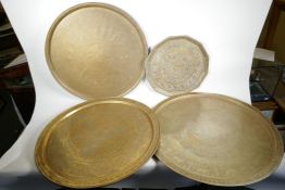 Four Islamic brass trays, all with engraved decoration, largest 26" diameter