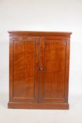 A Victorian mahogany two door cupboard, fitted with shelves, raised on a plinth base