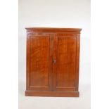 A Victorian mahogany two door cupboard, fitted with shelves, raised on a plinth base