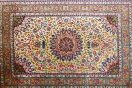 A Persian silk rug with floral medallion design on a white ground, 40" x 61"