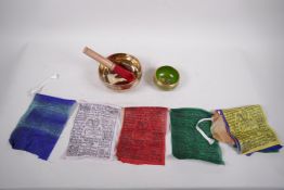 Two Tibetan brass singing bowls and a string of multicoloured prayer flags, 5½" diameter