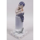 A Royal Copenhagen porcelain figurine of a young faun seated on a column playing panpipes to a