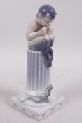 A Royal Copenhagen porcelain figurine of a young faun seated on a column playing panpipes to a