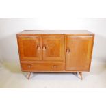 A mid C20th Ercol elm sideboard, with three cupboard doors and a single drawer, raised on turned