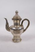 A Tibetan white metal teapot decorated with Buddhist emblems, double vajra mark to base, 8" high