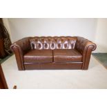 A leather button back Chesterfield settee, lacks feet, 73" wide