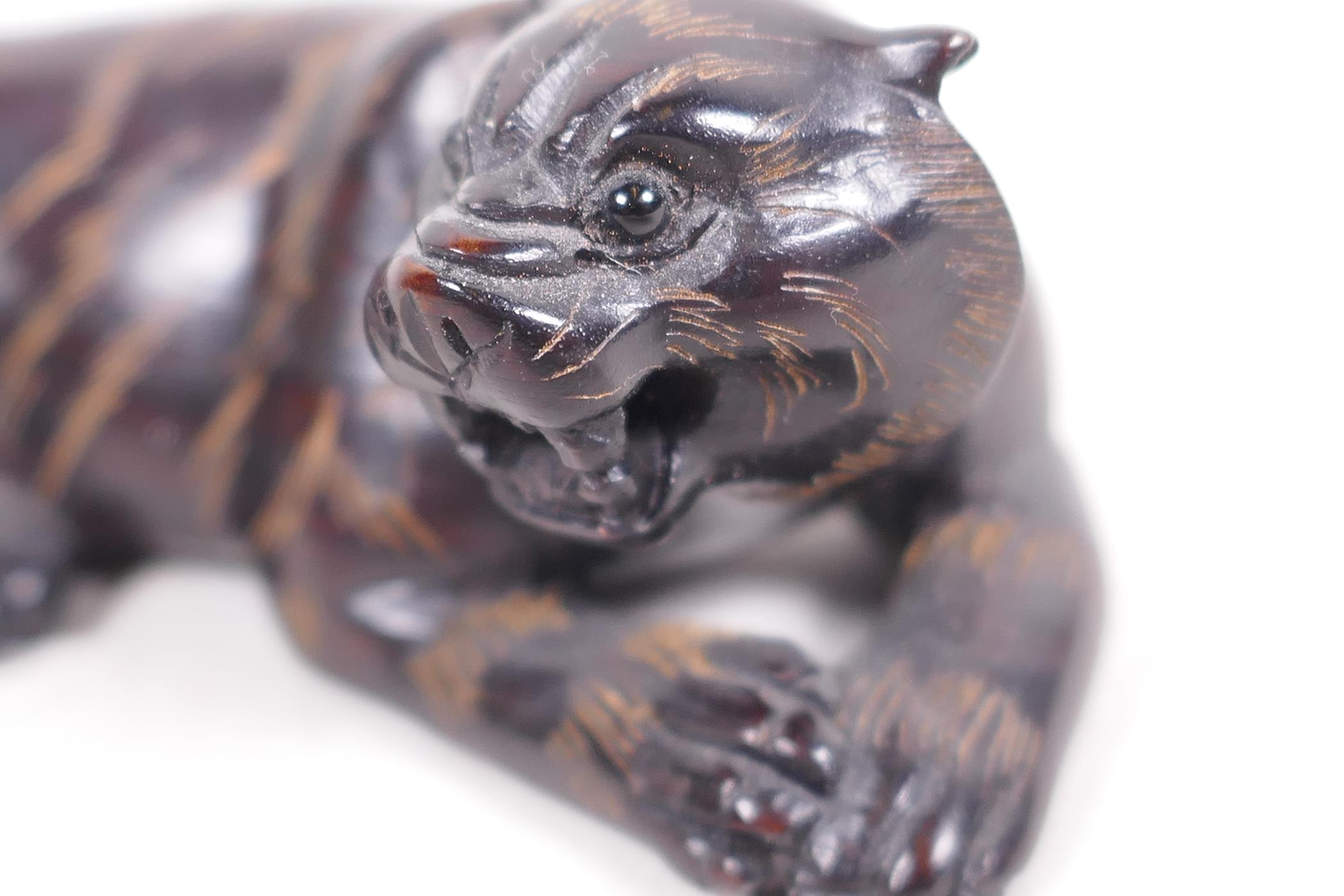 A carved hardwood netsuke in the shape of a tiger, signed on seal, 2½" long - Image 3 of 4