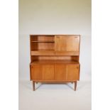 A mid C20th teak side cabinet with fall front and open shelves over two frieze drawers, and an