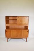 A mid C20th teak side cabinet with fall front and open shelves over two frieze drawers, and an