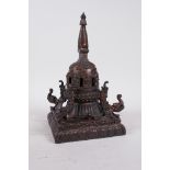 A Tibetan bronze stupa with a gilt patina, decorated with depictions of Buddha and mythical