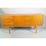 A mid C20th teak sideboard with three drawers and two cupboards, nickel plated handles, bears