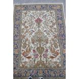 A Persian beige ground wool rug with a mirrored design of birds, trees and floral arrangements,