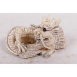 A bone netsuke carved as a coiled dragon with jet eyes, 1¾" long