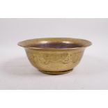 An oriental gilt copper bowl with raised decoration depicting a peacock in a cypress tree,