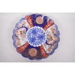 A Japanese Imari porcelain charger with frilled rim decorated with panels of garden scene with