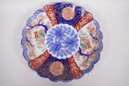 A Japanese Imari porcelain charger with frilled rim decorated with panels of garden scene with