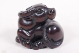 A carved hardwood netsuke in the form of a water buffalo, signed, 1½" wide