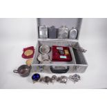 A flight case containing various silver plated items including hip flasks, cruets etc, and a