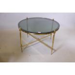 A brass and tinted glass occasional table with cross stretcher, 19" high x 31½" diameter