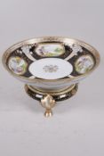 A Noritake porcelain fruit bowl on stand painted with panels of floral landscapes on a black