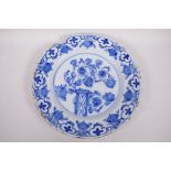An antique Delft tin glazed blue and white charger painted with flowers and fruit, chip to rim, 13½"