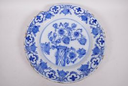 An antique Delft tin glazed blue and white charger painted with flowers and fruit, chip to rim, 13½"