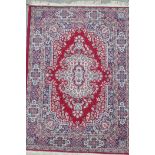 A red ground Persian pattern wool rug with a central floral medallion design, 47½" x 65"