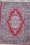 A red ground Persian pattern wool rug with a central floral medallion design, 47½" x 65"