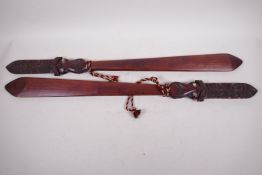 A pair of Maori carved wood short staffs, the handles carved as a face with mother of pearl eyes,
