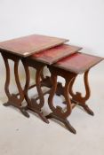 A nest of three mahogany occasional tables, with leather inset tops, raised on lyre shaped supports,