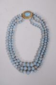 A graduated turquoise three strand necklace with a gilt metal clasp, 15½" long