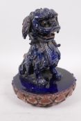 A blue glazed Chinese pottery figure of a kylin seated on a lotus shaped mount, A/F, 9" high