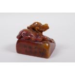 A Chinese mottled amber and red soapstone seal with carved decoration of a toad on a lily pad,