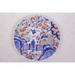 A C18th Dutch Delft tin glazed plate painted with birds and flowers in bright enamels, signed to