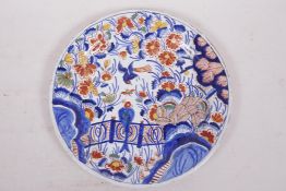 A C18th Dutch Delft tin glazed plate painted with birds and flowers in bright enamels, signed to