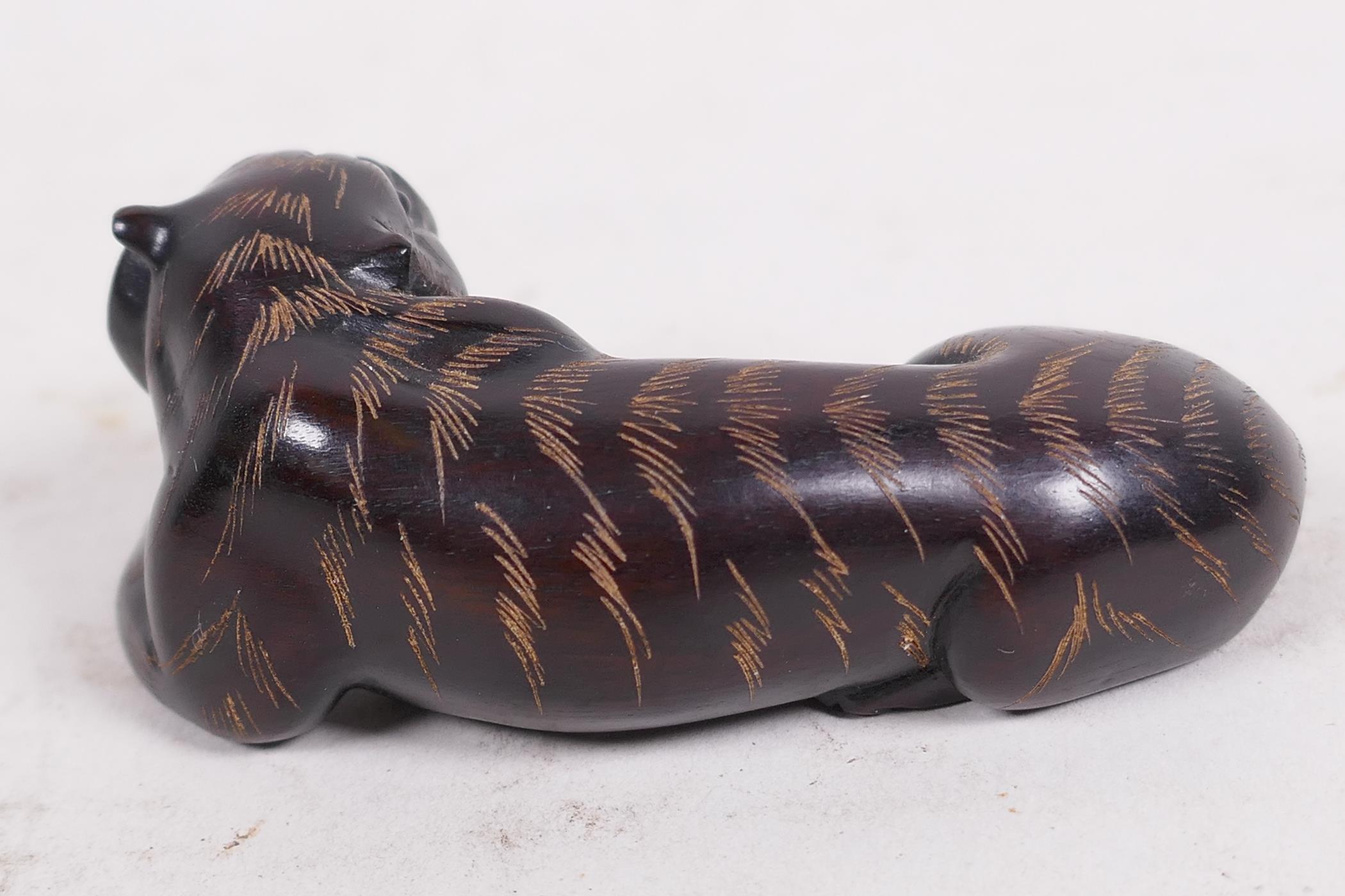 A carved hardwood netsuke in the shape of a tiger, signed on seal, 2½" long - Image 2 of 4