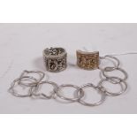 Two Chinese white metal nine link rings, with repousse decoration of a sage