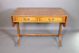 A Regency style yew wood veneered sofa table with two drawers, raised on pierced shaped ends with