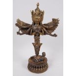 A Sino-Tibetan gilt bronze figurine of a wrathful winged deity with four faces and six arms, 11"