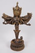 A Sino-Tibetan gilt bronze figurine of a wrathful winged deity with four faces and six arms, 11"