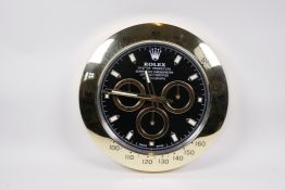 A quartz driven wall clock with gilt case and black face in the manner of a Daytona wristwatch, 13½"