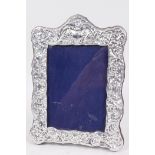 A sterling silver photo frame with pressed floral decoration, aperture 4" x 5½"