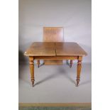 A Victorian mahogany drawleaf dining table with extra leaf, raised on turned supports and brass